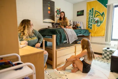 Three students sitting and talking in an NMU dorm room.