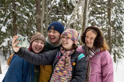 Four students taking a selfie while hiking in winter.