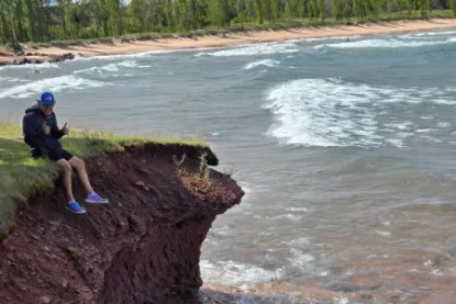 Cole Marsh sitting on a rocky cliff on the shore of Lake Superior. 