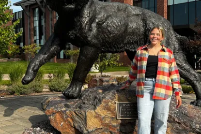 Rachel Rainszewski standing in front of NMU's wildcat statue. 