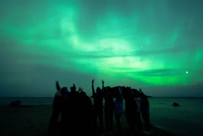Students on the beach at night watching the Northern Lights