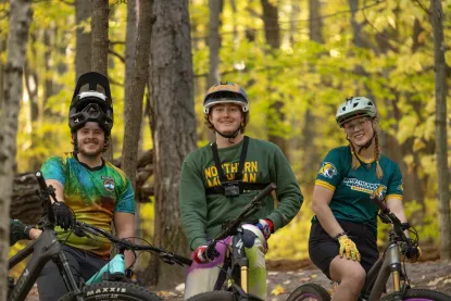 Three NMU students with their mountains bikes on a trail in the woods