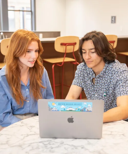 two students looking at a laptop