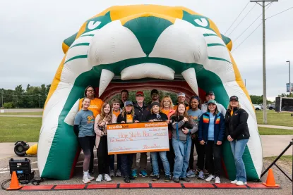 Group holding a big check in front of the inflatable NMU wildcat head