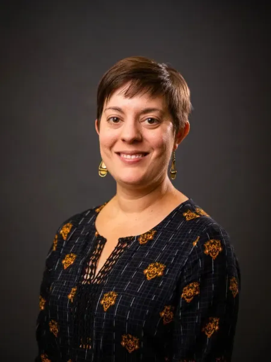 Woman in black blouse with decorations against dark background