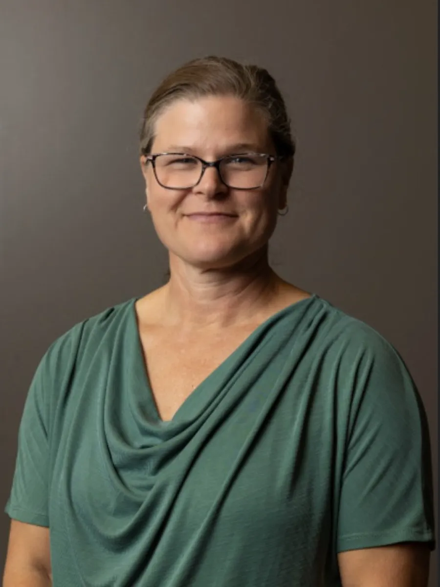 Headshot of woman with hair pulled back and green top.