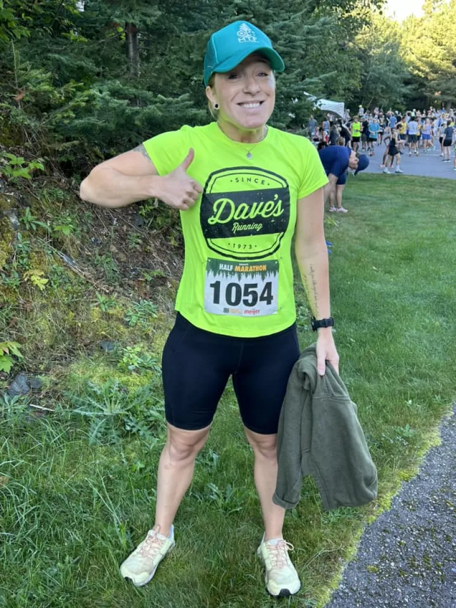 A photo of a woman in running attire, giving a thumbs up.