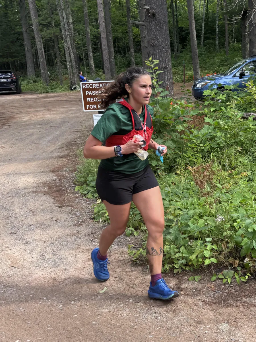 Woman in green shirt and black running shorts participating in a trail race.