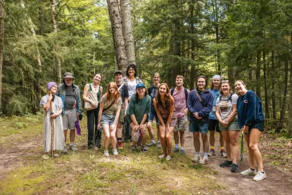Group of students standing on a hiking trail in the woods.