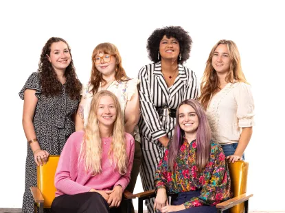 Team photo, where the graduate assistant and wellbeing promotions coordinator are seated in mustard-colored chairs, and the four peer educators are standing behind.