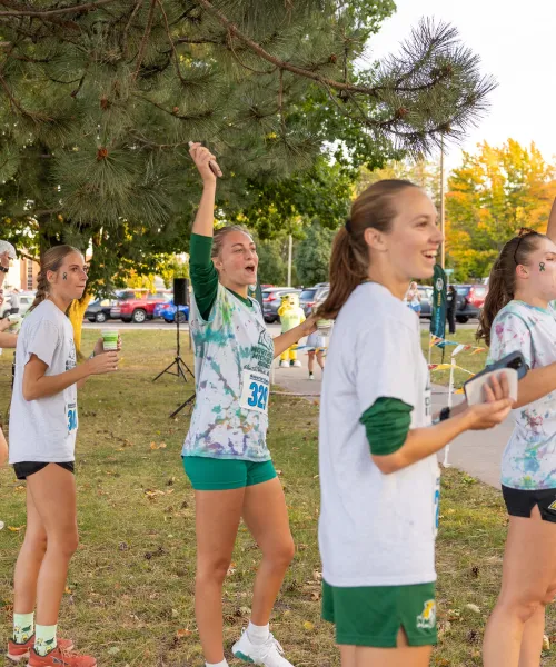 Five students cheer on teammates at the finish line.