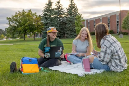 Three students sitting on a blanket and studying in the academic mall at NMU