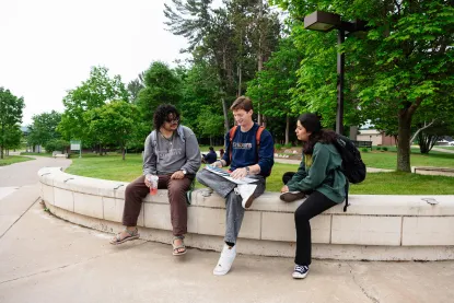 Three students sitting and talking in the academic mall at NMU