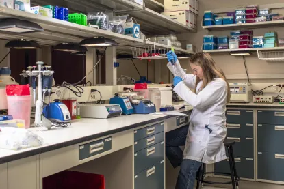 Student in a lab coat using a pipette in a lab